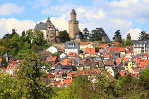 Una imagen de una ciudad llamada Königstein construida sobre una colina con una gran casa de piedra blanca en lo alto de la colina.