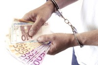 Ein Mensch der Geld in der Hand hält und Handschellen an hat